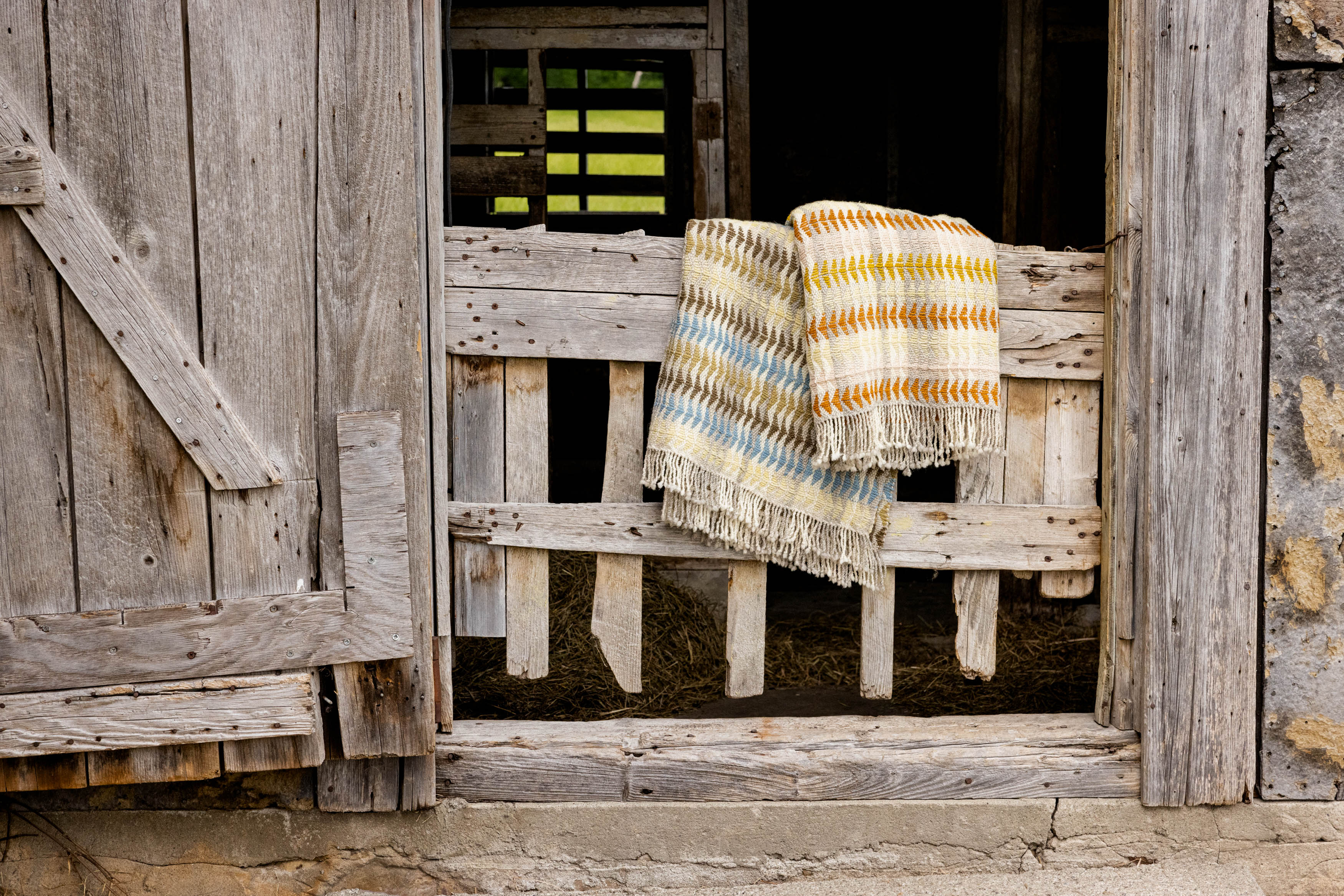 Wool blankets hanging on a barn door.